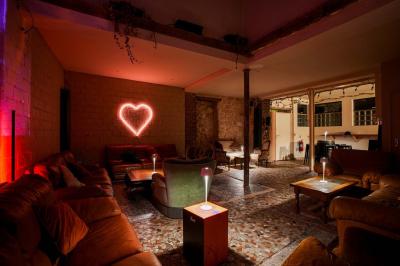 Miniature Location salle Nanterre (Hauts-de-Seine) - Les Enfants Terribles #7 Façade d'un café-restaurant avec terrasse vide, éclairée par des lumières colorées en soirée pluvieuse.