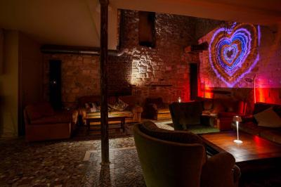 Miniature Location salle Nanterre (Hauts-de-Seine) - Les Enfants Terribles #6 Façade d'un café-restaurant avec terrasse vide, éclairée par des lumières colorées en soirée pluvieuse.