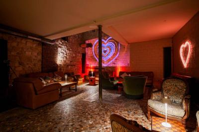 Miniature Location salle Nanterre (Hauts-de-Seine) - Les Enfants Terribles #5 Façade d'un café-restaurant avec terrasse vide, éclairée par des lumières colorées en soirée pluvieuse.