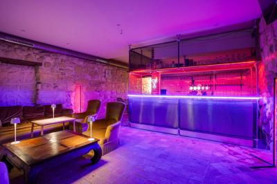 Miniature Location salle Nanterre (Hauts-de-Seine) - Les Enfants Terribles #3 Façade d'un café-restaurant avec terrasse vide, éclairée par des lumières colorées en soirée pluvieuse.