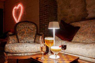 Miniature Location salle Nanterre (Hauts-de-Seine) - Les Enfants Terribles #12 Façade d'un café-restaurant avec terrasse vide, éclairée par des lumières colorées en soirée pluvieuse.