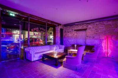 Miniature Location salle Nanterre (Hauts-de-Seine) - Les Enfants Terribles #4 Façade d'un café-restaurant avec terrasse vide, éclairée par des lumières colorées en soirée pluvieuse.