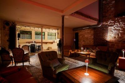 Miniature Location salle Nanterre (Hauts-de-Seine) - Les Enfants Terribles #8 Façade d'un café-restaurant avec terrasse vide, éclairée par des lumières colorées en soirée pluvieuse.