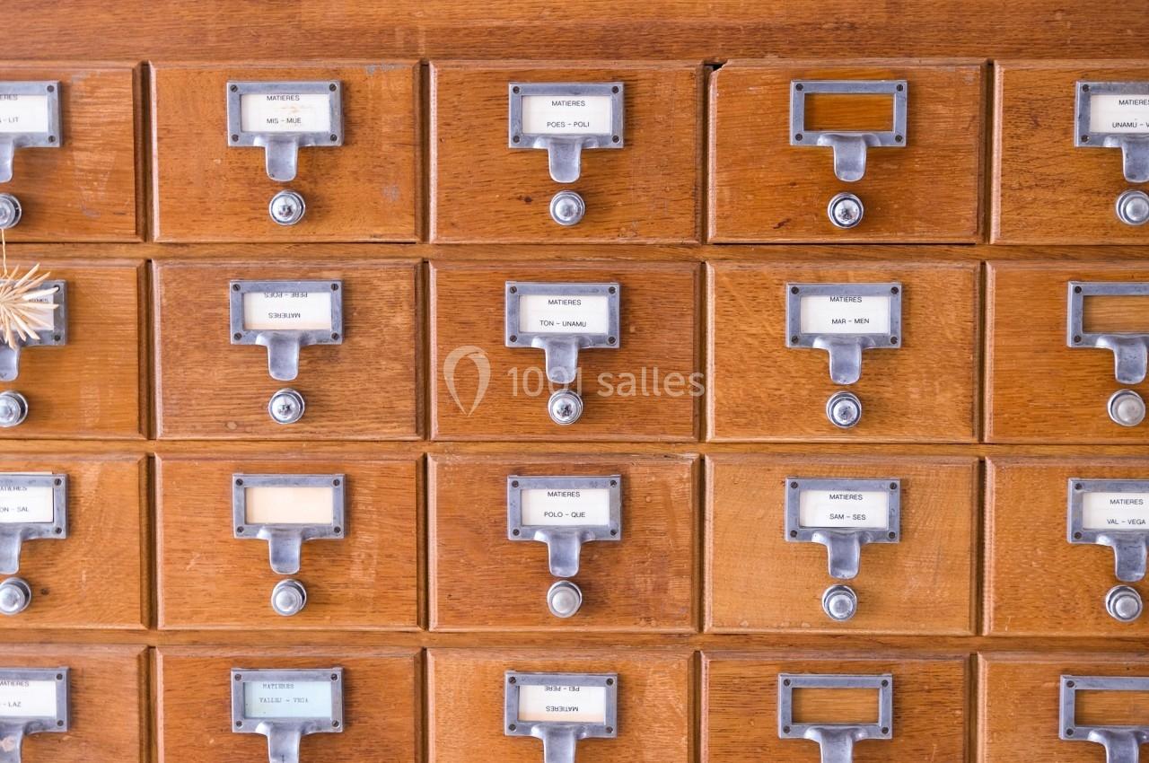 Tiroirs en bois d'un fichier de bibliothèque avec étiquettes et poignées métalliques alignés en rangées.