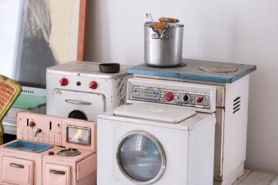 Collection de jouets anciens représentant des cuisinières miniatures et une balance rétro sur une étagère.