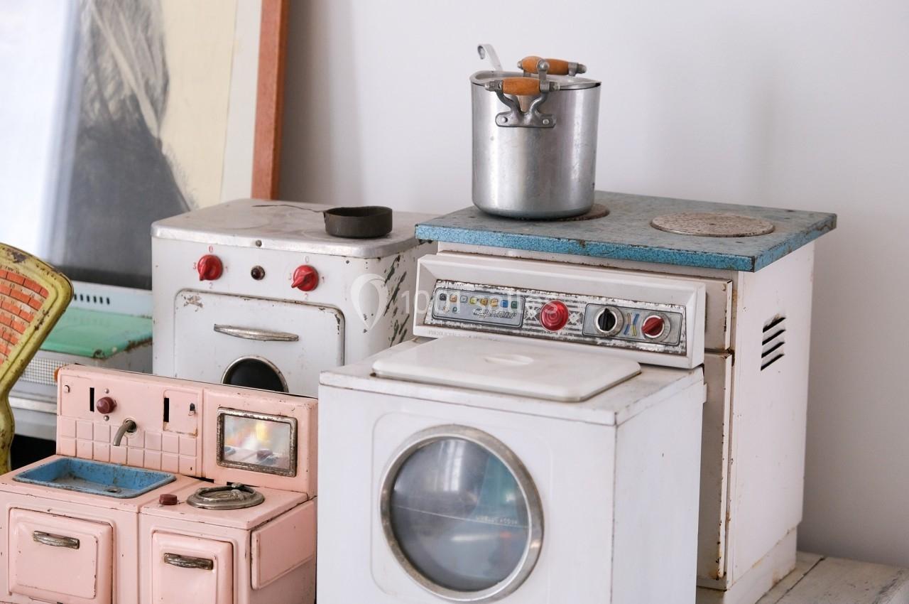 Jouets miniatures représentant des appareils électroménagers anciens, dont un four, une machine à laver et une cuisinière.