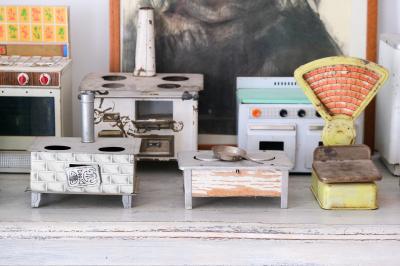 Collection de jouets anciens représentant des cuisinières miniatures et une balance rétro sur une étagère.