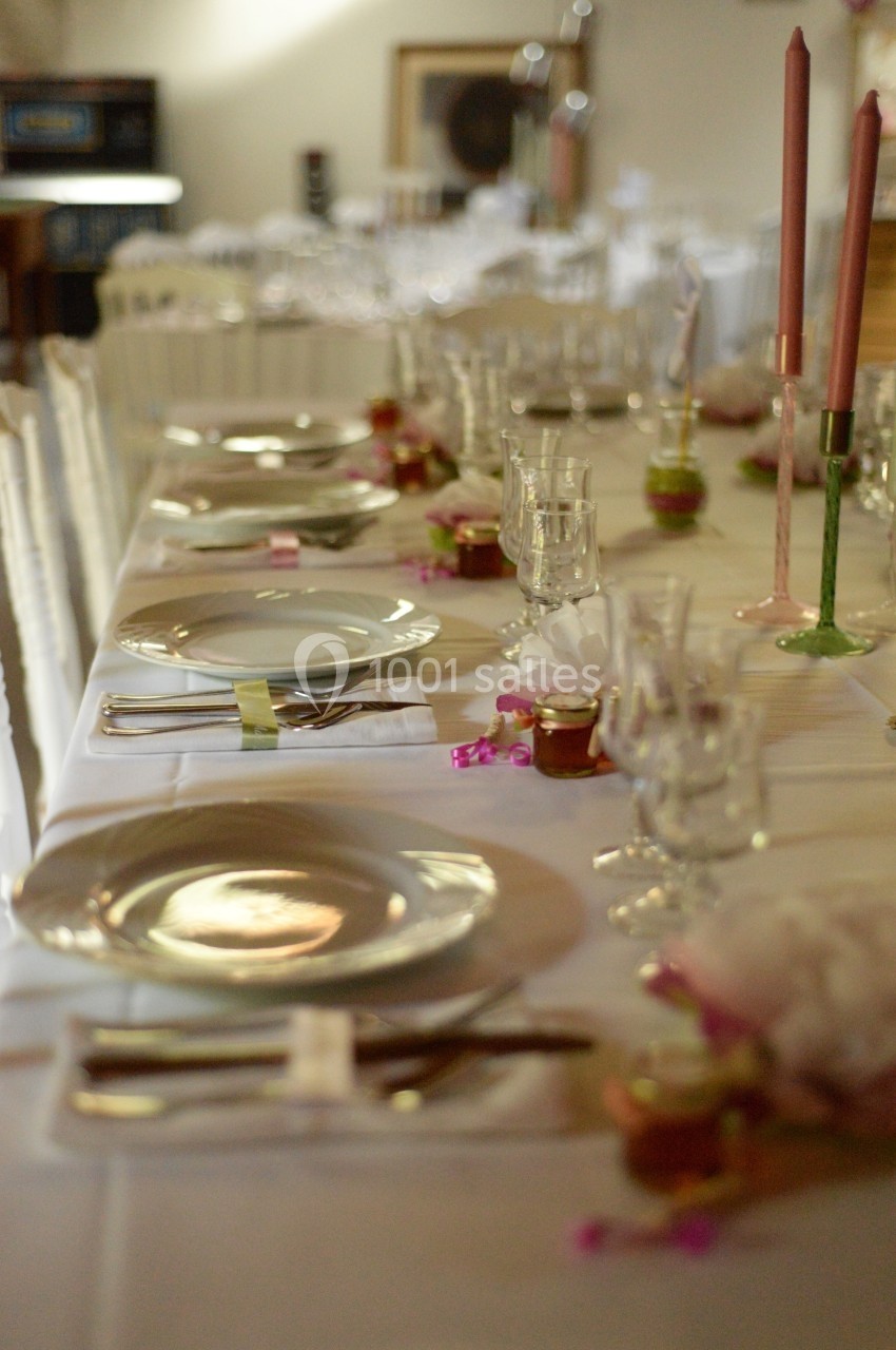 Table dressée avec vaisselle élégante, bougies roses et décorations florales pour un repas ou une réception.