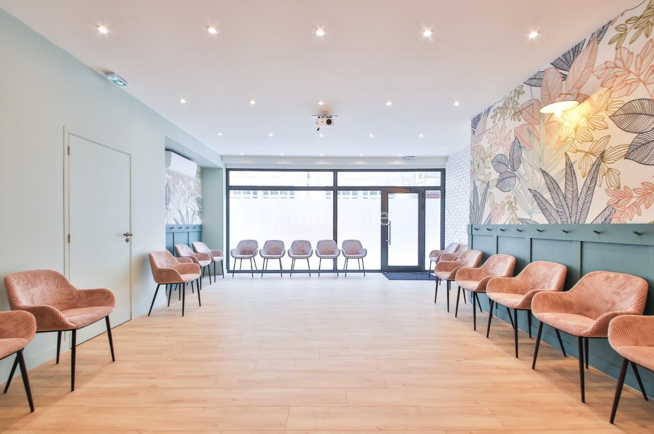 Salle d'attente lumineuse avec chaises roses alignées, murs décorés de motifs floraux et sol en bois clair.
