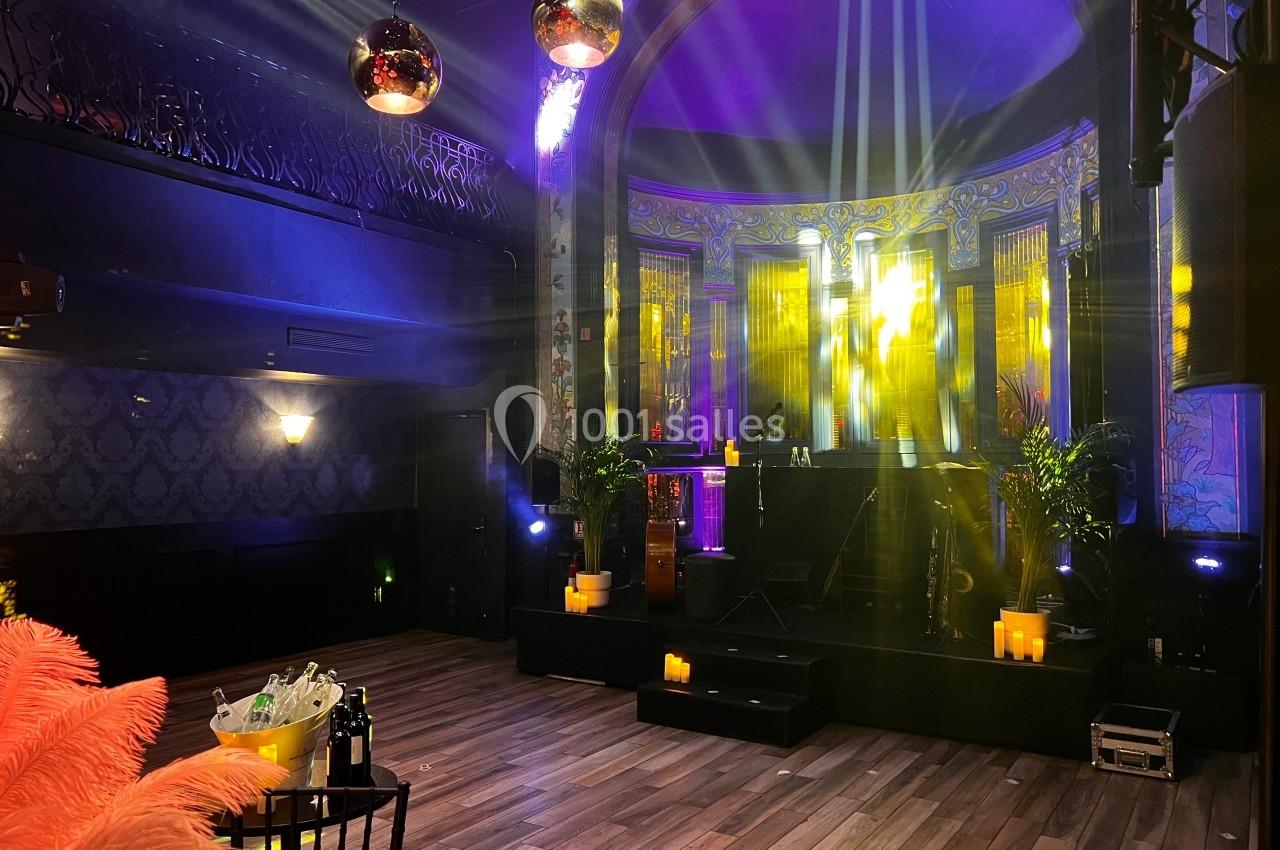 Salle de réception avec piste de danse, éclairages colorés, décorations élégantes et ambiance tamisée.