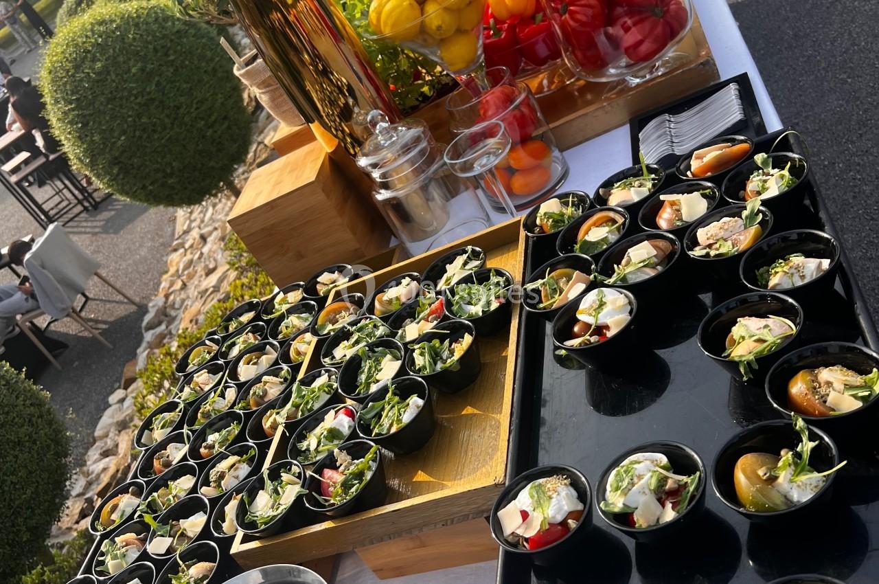 Buffet en extérieur avec verrines, salades et légumes colorés disposés sur une table blanche.