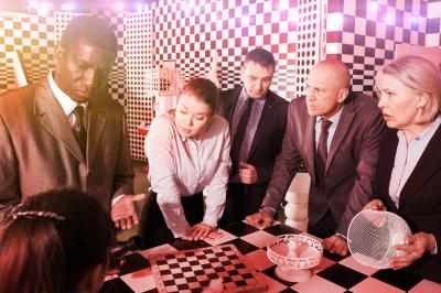 Personnes pratiquant le yoga sur une plage au coucher du soleil, en position debout avec les bras levés.