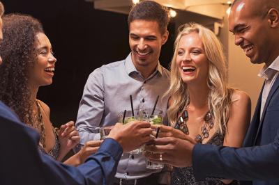 Personnes pratiquant le yoga sur une plage au coucher du soleil, en position debout avec les bras levés.