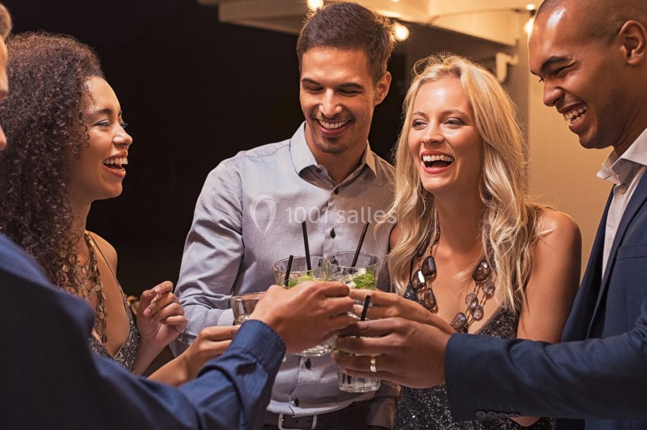 Un groupe de personnes souriantes trinque avec des verres lors d'une soirée en extérieur.