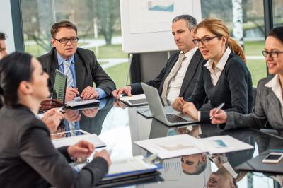 Personnes pratiquant le yoga sur une plage au coucher du soleil, en position debout avec les bras levés.