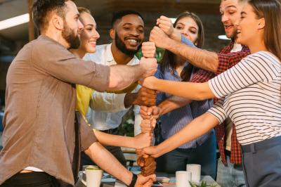 Personnes pratiquant le yoga sur une plage au coucher du soleil, en position debout avec les bras levés.