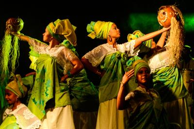 Un homme déguisé en Père Noël lit une lettre avec deux enfants souriants dans un décor chaleureux.