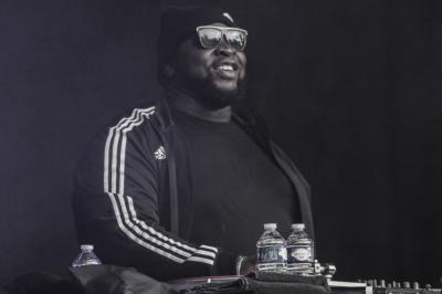 Un homme déguisé en Père Noël lit une lettre avec deux enfants souriants dans un décor chaleureux.