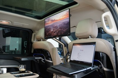 Vue intérieure d'un véhicule avec des sièges en cuir beige, un accoudoir avec porte-gobelet et un toit panoramique.