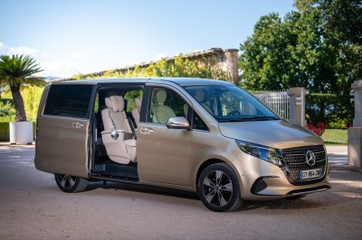 Vue intérieure d'un véhicule avec des sièges en cuir beige, un accoudoir avec porte-gobelet et un toit panoramique.