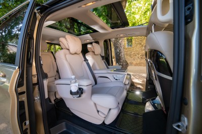 Vue intérieure d'un véhicule avec des sièges en cuir beige, un accoudoir avec porte-gobelet et un toit panoramique.