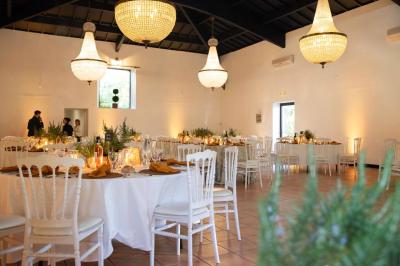 Salle spacieuse avec carrelage au sol, grandes baies vitrées, poutres apparentes et lustres suspendus.