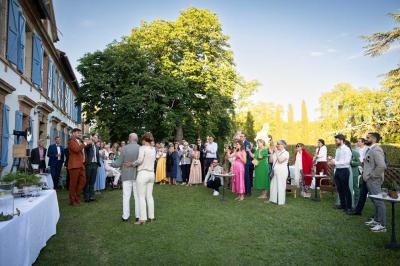 Salle spacieuse avec carrelage au sol, grandes baies vitrées, poutres apparentes et lustres suspendus.