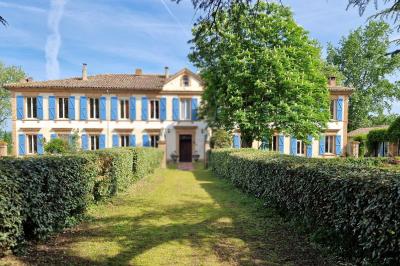 Salle spacieuse avec carrelage au sol, grandes baies vitrées, poutres apparentes et lustres suspendus.