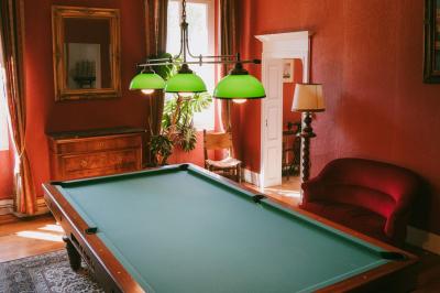 Salle spacieuse avec carrelage au sol, grandes baies vitrées, poutres apparentes et lustres suspendus.