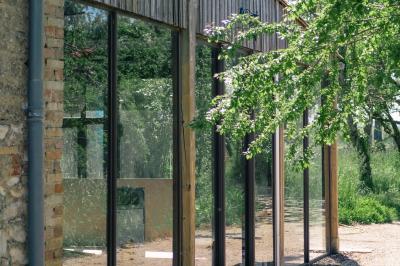 Salle spacieuse avec carrelage au sol, grandes baies vitrées, poutres apparentes et lustres suspendus.
