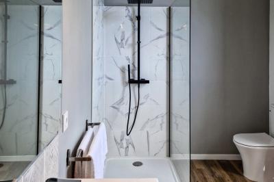 Salle spacieuse avec carrelage au sol, grandes baies vitrées, poutres apparentes et lustres suspendus.