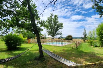 Salle spacieuse avec carrelage au sol, grandes baies vitrées, poutres apparentes et lustres suspendus.
