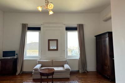 Salle spacieuse avec carrelage au sol, grandes baies vitrées, poutres apparentes et lustres suspendus.