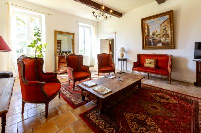 Salle spacieuse avec carrelage au sol, grandes baies vitrées, poutres apparentes et lustres suspendus.