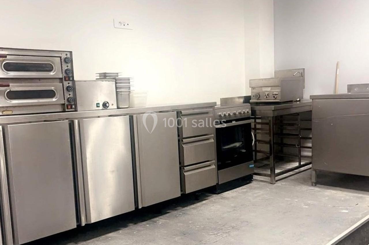 Cuisine professionnelle avec équipements en inox, comprenant fours, plaques de cuisson, étagères et plans de travail.