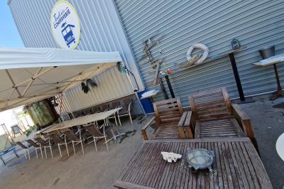 Des personnes assises à des tables sous une pergola ombragée, discutant et partageant un moment convivial.