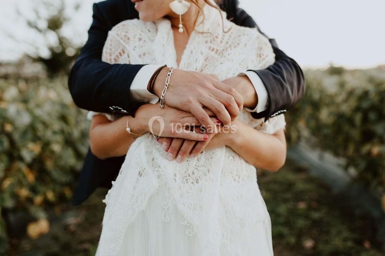Un couple en tenue de mariage s'enlace tendrement dans un vignoble au coucher du soleil.