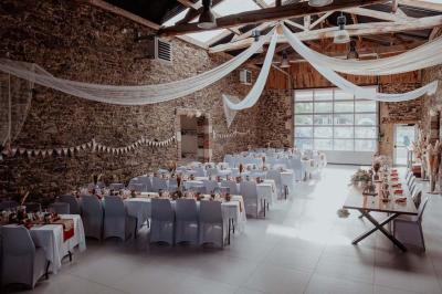 Salle décorée avec des fûts recyclés en tables, éclairage chaleureux et éléments rustiques en bois.