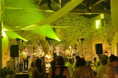 Salle décorée avec des fûts recyclés en tables, éclairage chaleureux et éléments rustiques en bois.
