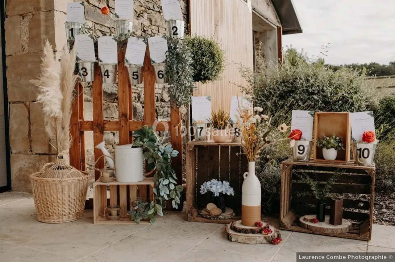 Décoration champêtre avec cagettes en bois, fleurs, plantes et numéros de table pour un événement en extérieur.