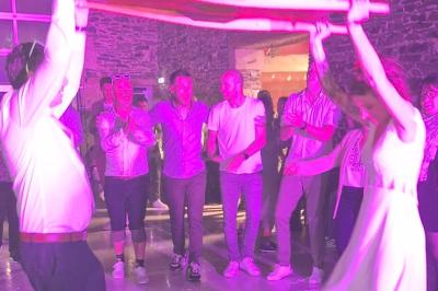 Salle décorée avec des fûts recyclés en tables, éclairage chaleureux et éléments rustiques en bois.