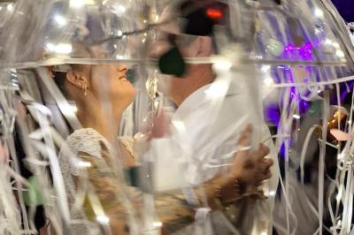 Salle décorée avec des fûts recyclés en tables, éclairage chaleureux et éléments rustiques en bois.