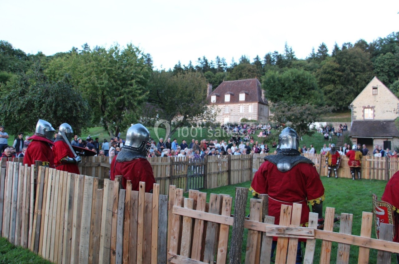 Des chevaliers en armure participent à une reconstitution médiévale devant un public rassemblé en plein air.