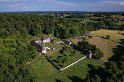 Salon rustique avec murs en pierre, canapés en cuir, table basse et porte ouverte donnant sur un jardin ensoleillé.