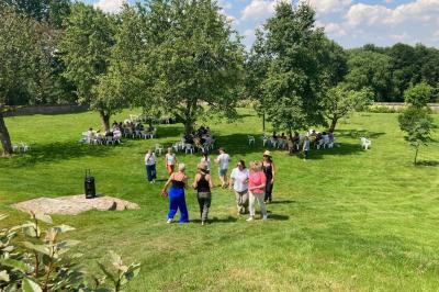 Salon rustique avec murs en pierre, canapés en cuir, table basse et porte ouverte donnant sur un jardin ensoleillé.