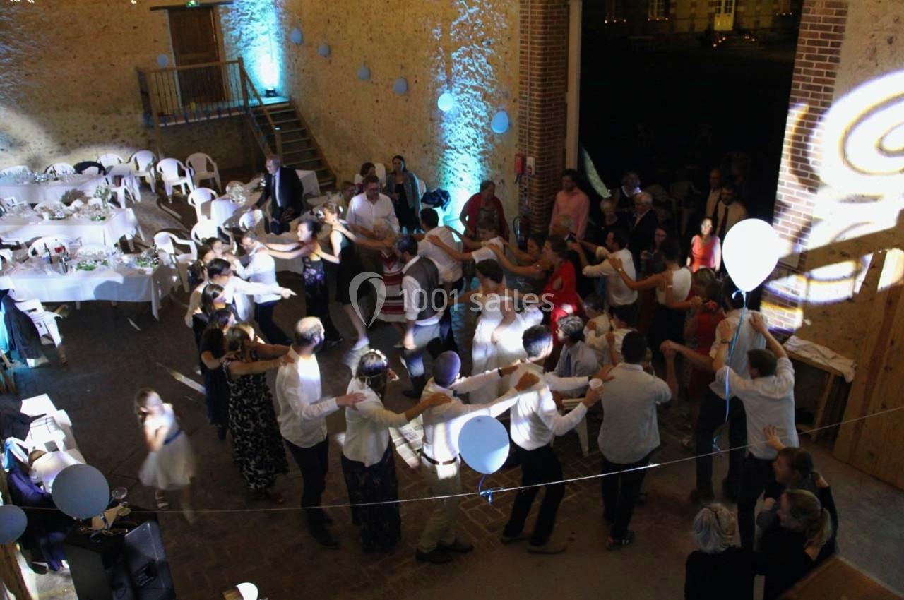 Groupe de personnes dans une salle décorée, dansant en cercle lors d'une fête ou d'un événement festif.