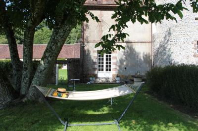 Salon rustique avec murs en pierre, canapés en cuir, table basse et porte ouverte donnant sur un jardin ensoleillé.