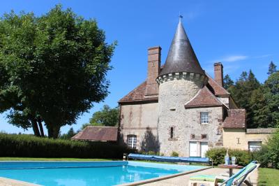 Salon rustique avec murs en pierre, canapés en cuir, table basse et porte ouverte donnant sur un jardin ensoleillé.