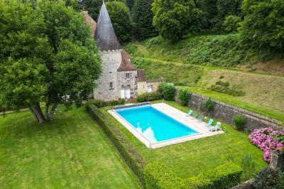 Salon rustique avec murs en pierre, canapés en cuir, table basse et porte ouverte donnant sur un jardin ensoleillé.