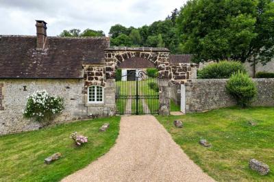 Salon rustique avec murs en pierre, canapés en cuir, table basse et porte ouverte donnant sur un jardin ensoleillé.